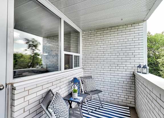 a balcony with two chairs and a table and a window