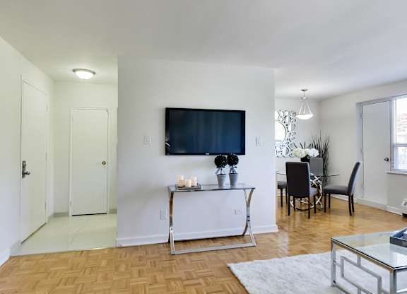 a living room with a tv on the wall and a dining room table