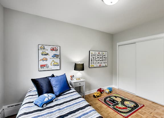 a bedroom with a bed with blue pillows and a toy car