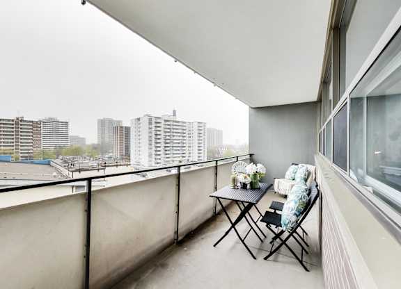 a balcony with a table and chairs and a view of the city
