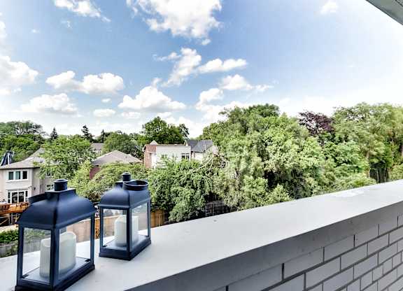 a balcony with two blue lanterns and a view of trees and houses