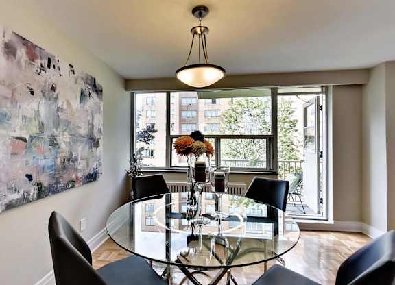 a dining room with a glass table and chairs and a large window