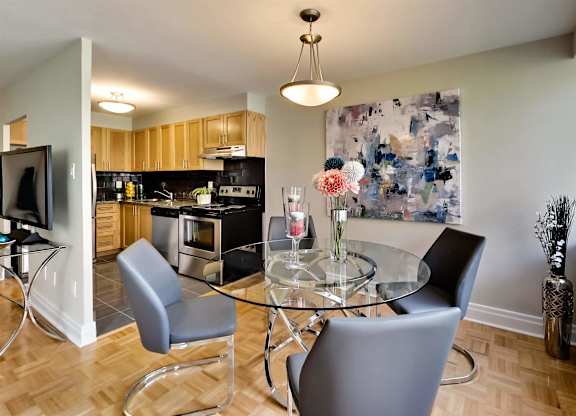 a dining room with a glass table and chairs and a kitchen