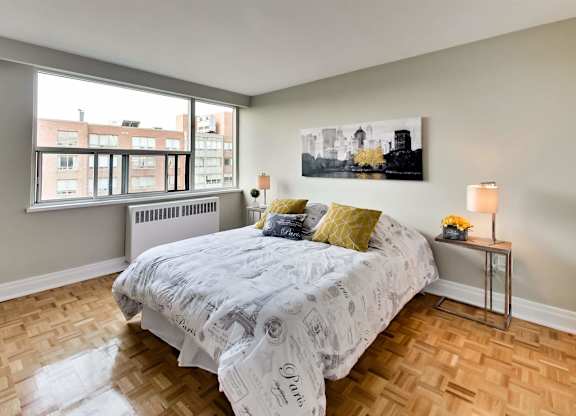 a bedroom with a bed and a large window and wooden floors