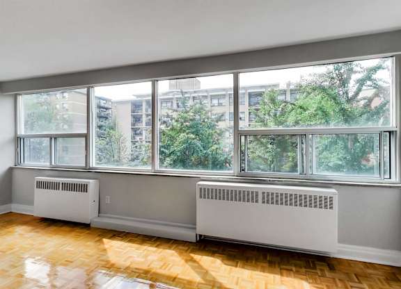 an empty living room with a large window and a wood floor