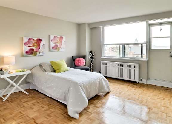 a bedroom with a bed and a window and a wooden floor