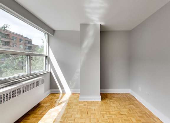 an empty living room with a large window and wood floors