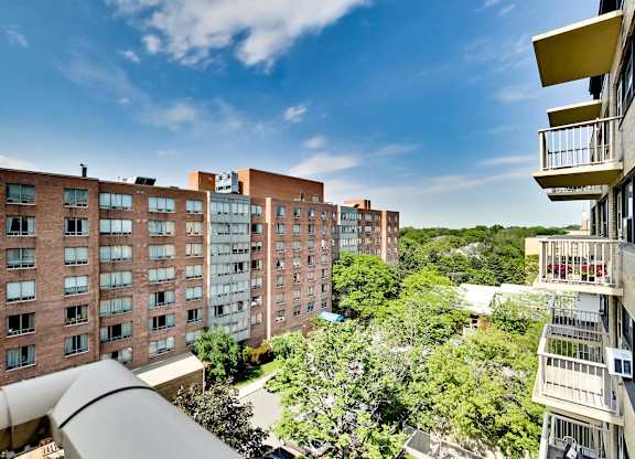 a view of apartment buildings from a balcony with trees