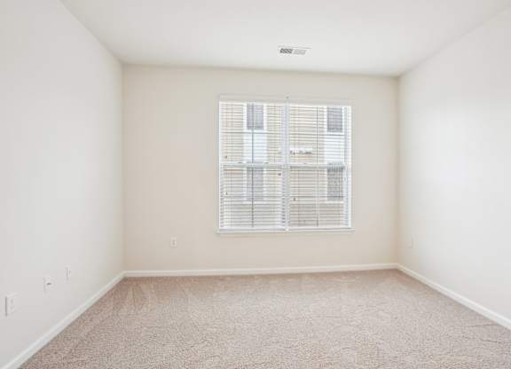 A room with a window covered by white blinds.