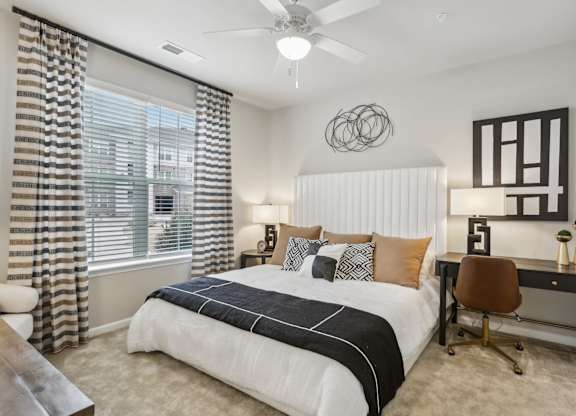 a large bedroom with a ceiling fan and large window