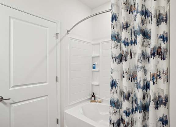 A white bathroom with a blue and white shower curtain.