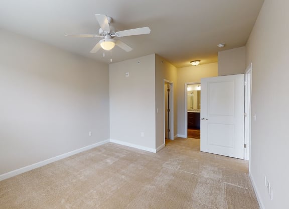 Bedroom with ceiling fan, carpet and door to bathroom