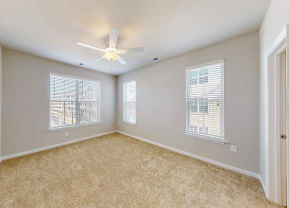 a spacious bedroom with a ceiling fan and windows