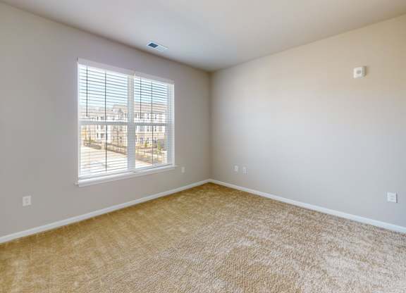 a large bedroom with plush carpet and a large window