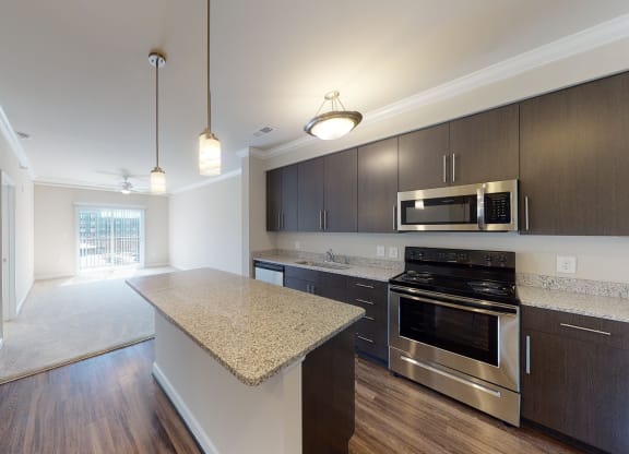 Kitchen with brown cabinets, stainless steel appliances and granite countertops; open to living room