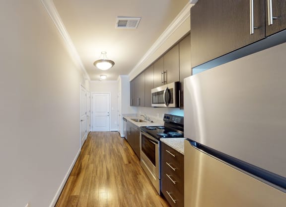 Kitchen with dark cabinets, granite countertops, vinyl wood plank floors