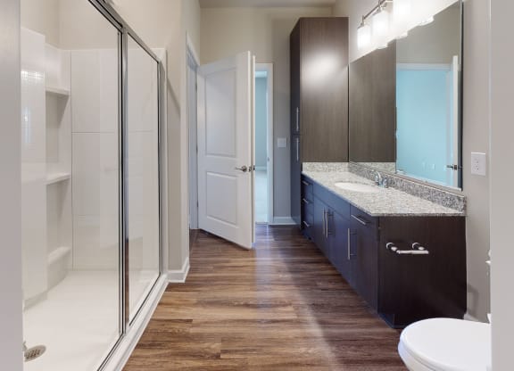 Bathroom with shower, dark cabinets, vinyl floors