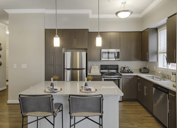 Kitchen with island, dark cabinets, vinyl floors and granite countertops