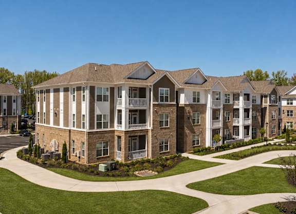 A large, multi-story residential building with a landscaped front yard.