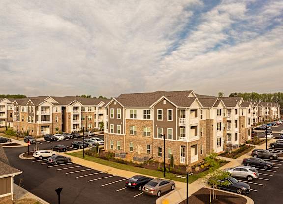 A large apartment complex with a parking lot in front.