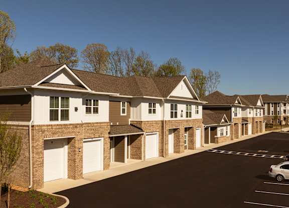 A row of houses with cars parked in front.