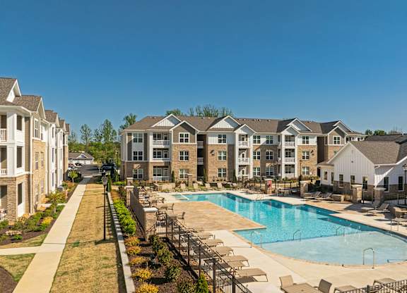 A swimming pool surrounded by lounge chairs and apartment buildings.