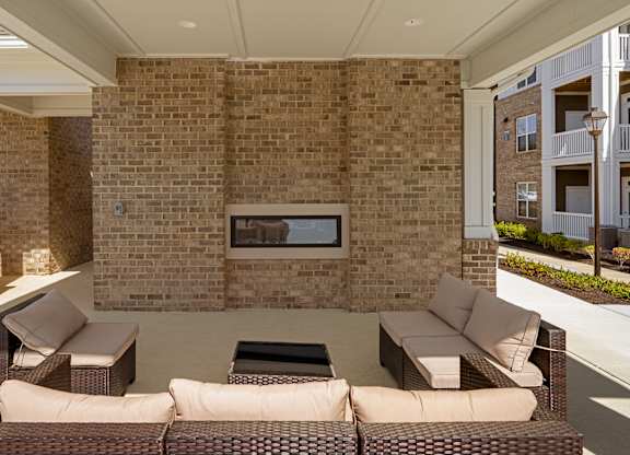 A patio with a couch, chair, and fireplace.