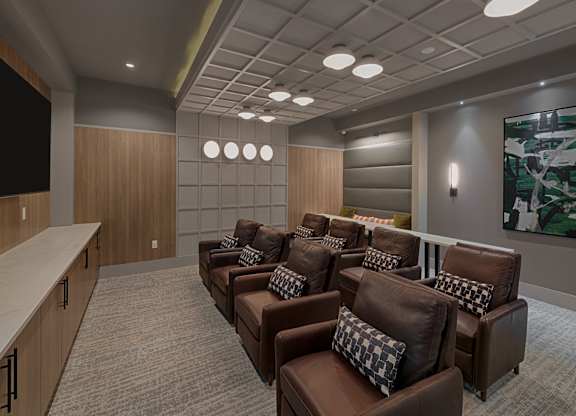 A conference room with brown leather chairs and a television on the wall.
