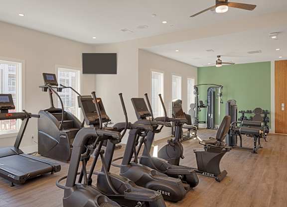 A gym with treadmills, elliptical machines, and a weight room.