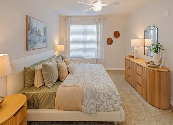 A bedroom with a bed, nightstand, and a painting on the wall.