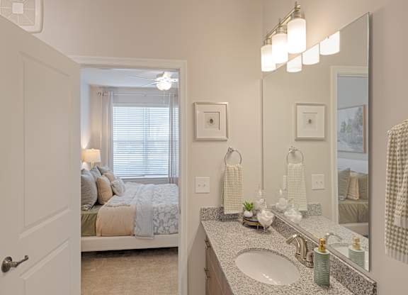 A bathroom with a bedroom view through the window.