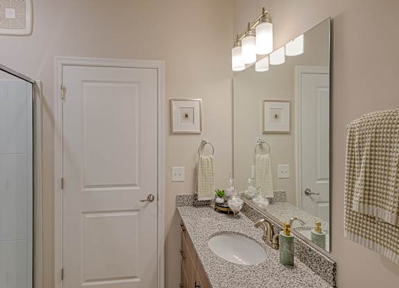A bathroom with a sink, mirror, and towel rack.