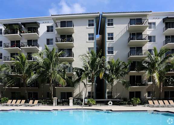An apartment building with a pool in front of it.