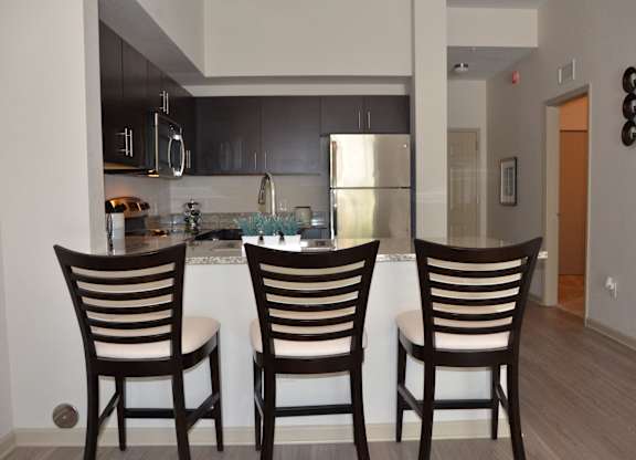 Three wooden chairs are placed in front of a kitchen island.