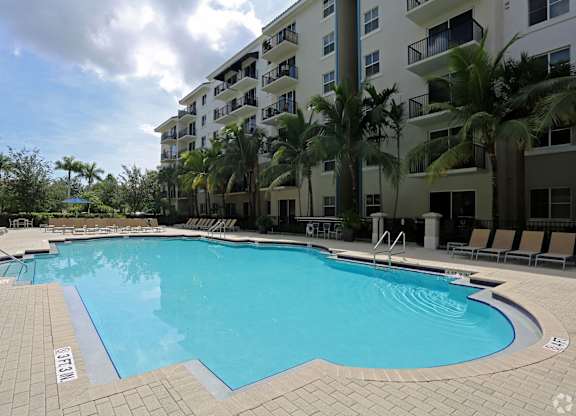 A swimming pool surrounded by palm trees and apartment buildings.