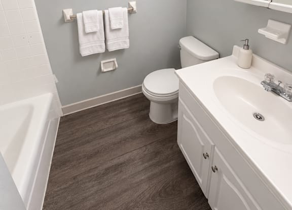 A white bathroom with a toilet, sink, and towel rack.