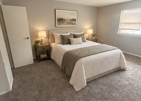 A bedroom with a large bed and a painting on the wall.