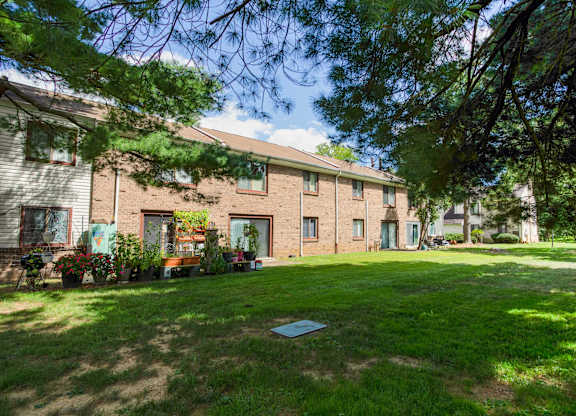 A house with a green lawn and trees in the background at Brookshire Trace Townhomes Apartments, Pennsylvania