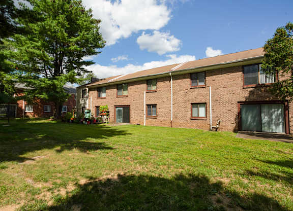 A grassy area in front of a brick building with trees on the left at Brookshire Trace Townhomes Apartments, Pennsylvania