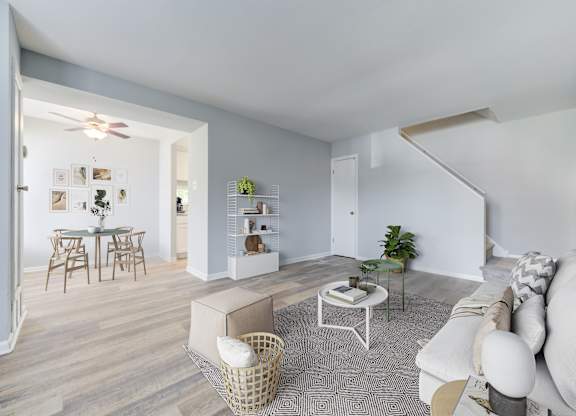 A living room with a white couch, a coffee table, and a dining table with chairs.