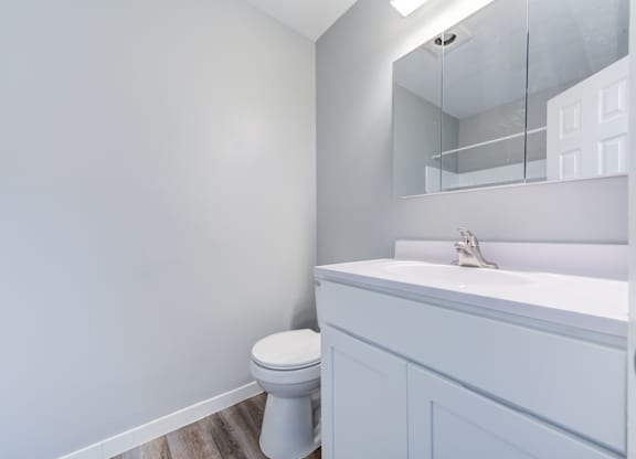 A white toilet sits in a bathroom next to a sink.