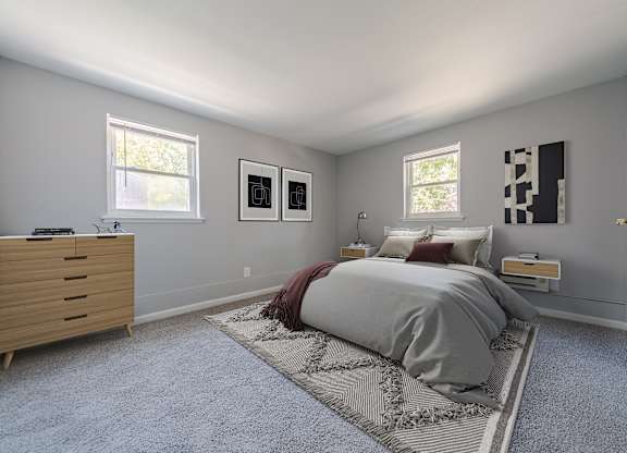 A bedroom with a bed, dresser, and two windows.