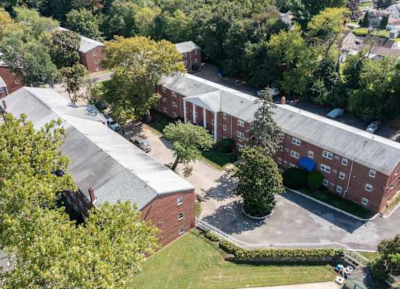 A large red brick building with a parking lot in front.at Grant Meadows Apartments, Philadelphia, PA