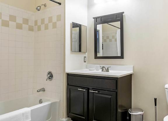 A bathroom with a white toilet, a white sink, a black vanity, and a white bathtub.at Riverview Landing @ Valley Forge, Pennsylvania