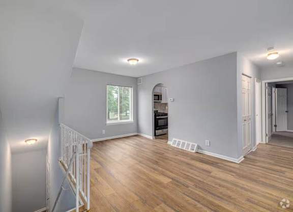 A spacious living room with wooden floors and white walls at Brookshire Trace Townhomes Apartments, Philadelphia, PA