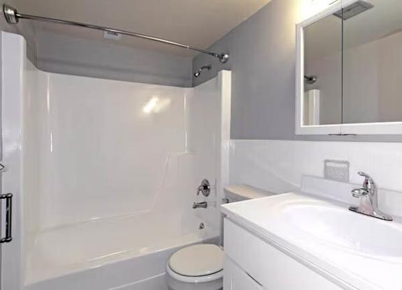 A white bathroom with a toilet, sink, and mirror at Brookshire Trace Townhomes Apartments, Philadelphia, Pennsylvania
