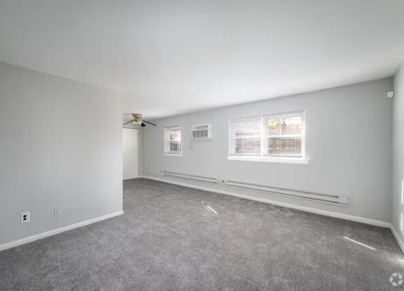 A spacious room with a ceiling fan and two windows.at Grant Meadows Apartments, Philadelphia, PA