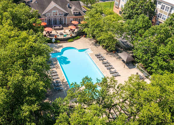 A large swimming pool surrounded by trees and a building in the background.