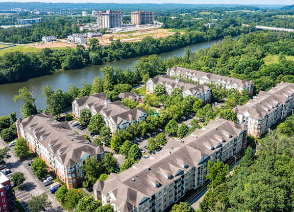 A large apartment complex is surrounded by trees and overlooks a river.