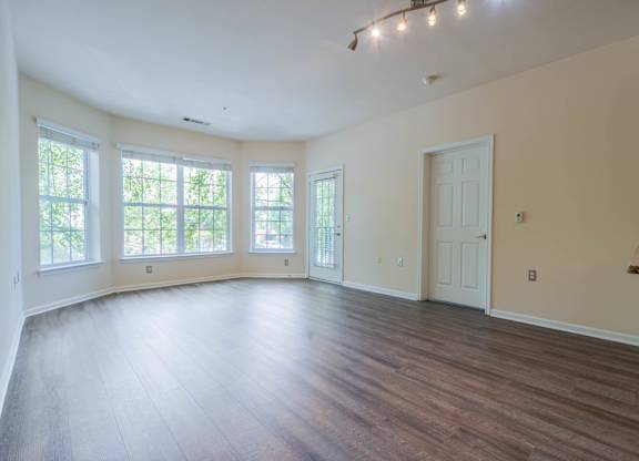 A large empty room with wooden floors and white walls.